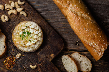 Baked Camembert cheese on a wooden board. Baguette