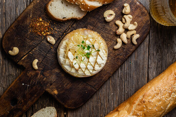 Baked Camembert cheese on a wooden board. Baguette