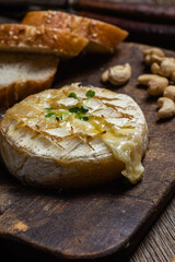 Baked Camembert cheese on a wooden board. Baguette