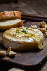 Baked Camembert cheese on a wooden board. Baguette