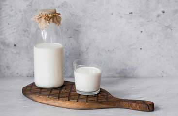 Organic natural cow's milk in a glass bottle and glass on a stylish wooden board on a stone table....