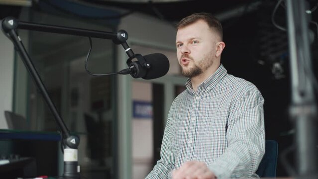 Handsome smiling radio host working in studio with microphone.