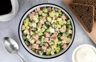 Russian cold soup - okroshka with vegetables, sausage, herbs, kvass and black bread on a gray background. Top view.