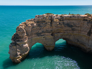 Aerial view of natural stone arches and blue ocean in Marinha Beach, Southern Portugal 