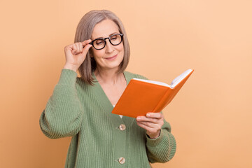 Photo of concentrated school teacher old lady hold literature touch specs enjoy nonfiction materials isolated on beige color background