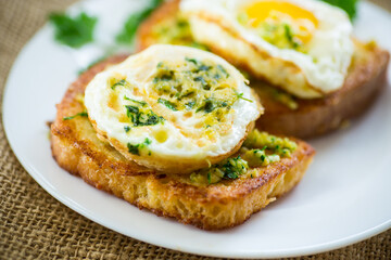 Fried croutons in batter with garlic and herbs and a fried egg in a plate.