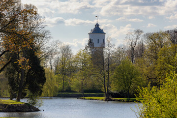 Fototapeta premium Spring landscape with green leaves on the tree, Warm sunny sunlight, Van Heutsz Park and water tower as background, Coevorden is a city and municipality in the province of Drenthe, Netherlands.