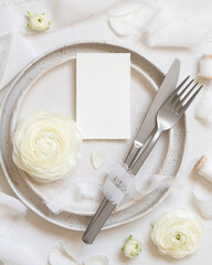 Wedding table setting with small card near cream roses and white silk ribbons top view, mockup