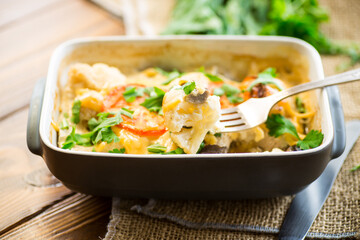 cauliflower baked with chicken fillet and mushrooms under cheese in a ceramic form