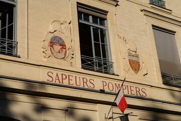 Façade d’une caserne des Sapeurs Pompiers de Paris, avec un drapeau français, le blason de la...