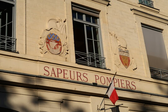 Fa&ccedil;ade d&rsquo;une caserne des Sapeurs Pompiers de Paris, avec un drapeau fran&ccedil;ais, le blason de la ville et le blason mentionnant la devise du sapeur pompier de Paris "Sauver ou p&eacute;rir" (France)
