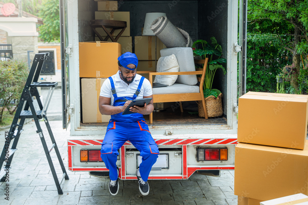 Poster House moving service worker unloading boxes and checking list before sending them to the homeowner.