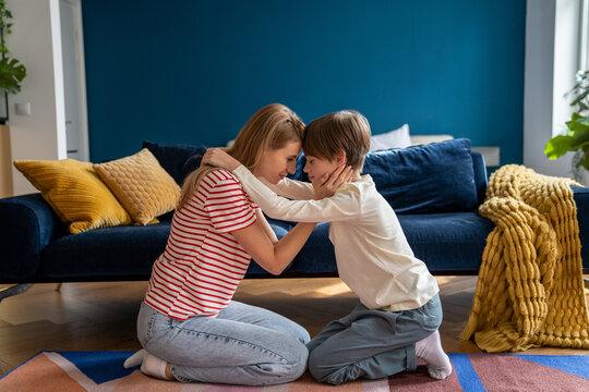 Affectionate Empathic Caring Mom And Teen Son Hug Together Sit On Floor In Living Room At Home With Closed Eyes. Family Supporting Helping. Mother Comforting Consoling Boy. Teenage Problems Concept.