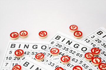 Many wooden chips with numbers and cards for a board game of bingo or lotto on a light background.