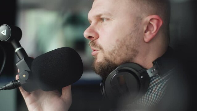 Handsome smiling radio host working in studio with microphone and headphones.