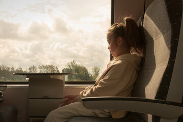 Girl on the evening train. Bored teenager in front of a train window at sunset © kinovo