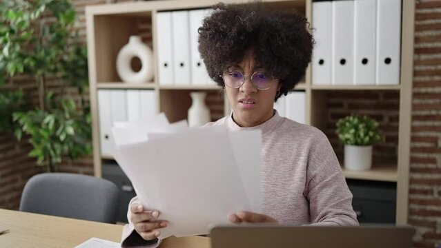 Young african american woman business worker holding dollars reading document at office