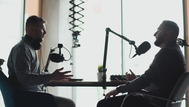 Two podcasters laughing and having fun in the studio. Two happy young people are doing a live audio broadcast together.
