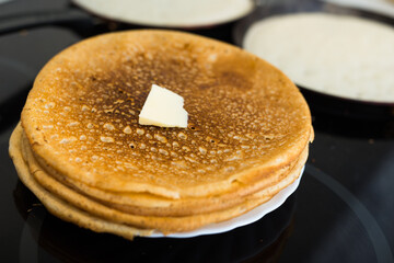 hot golden pancakes made from grain flour in kitchen while cooking on pans and on plate