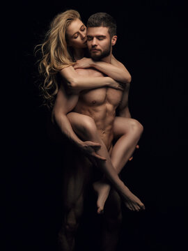 Two naked people on black background. Handsome couple in studio. Beautiful blond girl riding on fitness male model back.