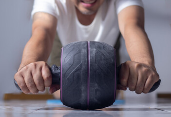 Man doing abdominal roller exercises to strengthen abdominal muscles at home.