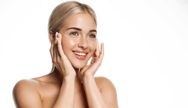 Spa and cosmetology. Young blond woman smiling happy, looking up, holding hands on face, applies moisturizing cream, face lotion or toner, white background