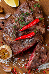 Grilled juicy steak on a wooden board with pepper and salt 
