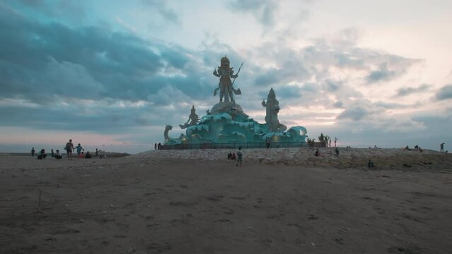 Pantai Jerman (German Beach) in Kuta, Bali Indonesia sunset shot showing statue of Varuna (The God of Sky, Water and Ocean) with people walking