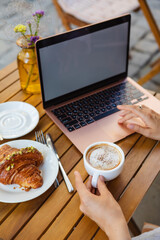 Surfing the web on a laptop in a summer cafe with a croissant and coffee