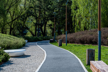 Obraz premium A winding asphalt pedestrian path in the park on a spring day.