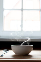 Fototapeta na wymiar Bowl of soup next to a window. Steam of hot soup. Warm food