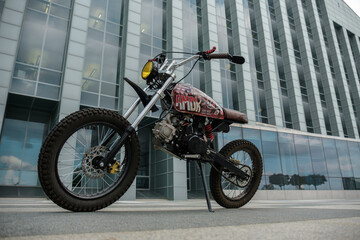 Shot of vintage style motorbike against huge city building in daytime.