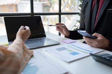 Business team and two colleagues discussing data from graph Financial charts and documents , mobile phone to contact negotiations New planning on office table with laptop startup business ideas.