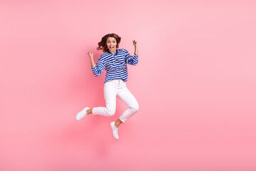 Fototapeta na wymiar Full length photo of crazy overjoyed woman jump fists up big sale black friday shopaholic wear striped shirt isolated on pink background