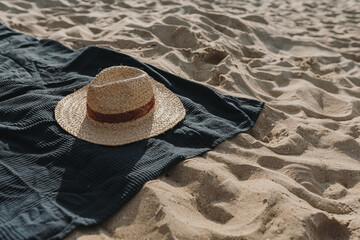 Straw hat, beach towel on beach sand. Minimal fashion vogue background. Flat lay, top view