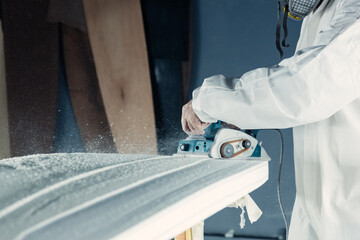 Anonymous professional master polishing surfboard in workshop