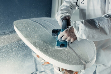 Anonymous professional master polishing surfboard in workshop