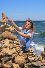 A young woman is trying to complete a cairn.
