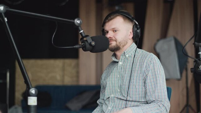 Handsome smiling radio host working in studio with microphone and headphones.