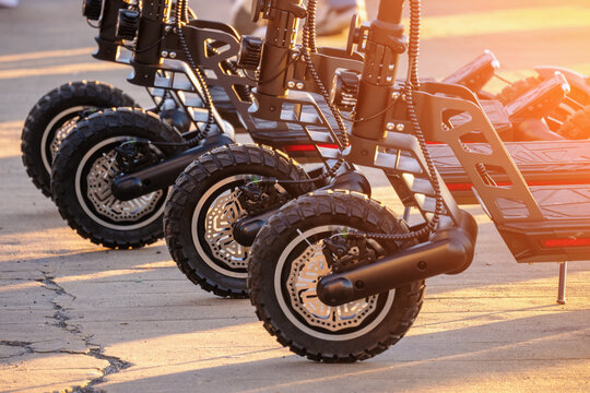 Electric push scooters for rent parked in city park. Eco transport of future concept, close up on wheels standing in row.