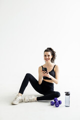 Full body fitness trainer instructor woman use mobile phone drink water train do exercises at home gym indoor.