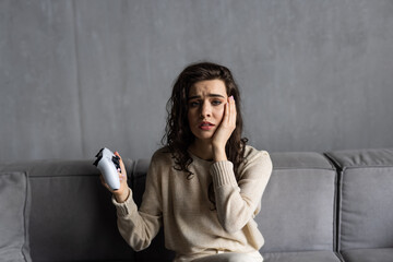 Fototapeta premium Emotional young woman playing video games sit on couch at home