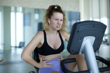 Fototapeta premium Young sad fat frustrated woman train at gym, doing cardio exercise trying to lose weight and drink water 