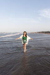 A young Hispanic woman is posing in the sea water at the beach