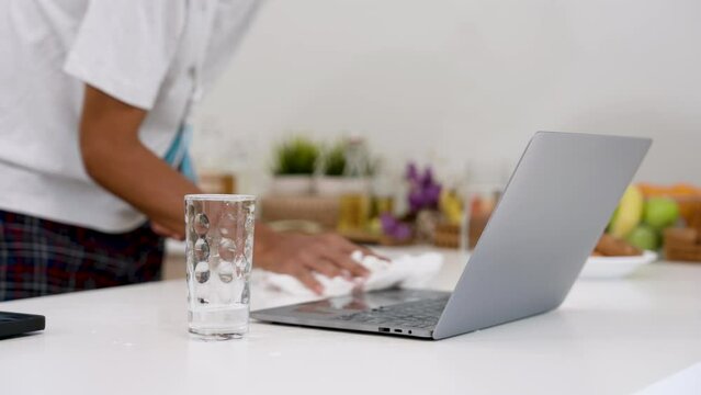Close-up wet laptop computer because men spilled water from glass that was, was using right hand wipe spilled water towel, because left hand had an accident put on an arm brace rest arm temporarily.