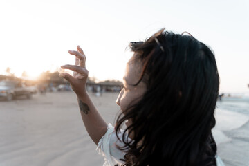 A young Hispanic woman is admiring a found seashell during sunset