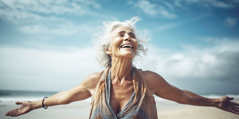 Happy senior woman standing on the beach with open arms, enjoying summer and freedom