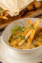 Bowl of tasty Sopa de Lima soup on wooden table
