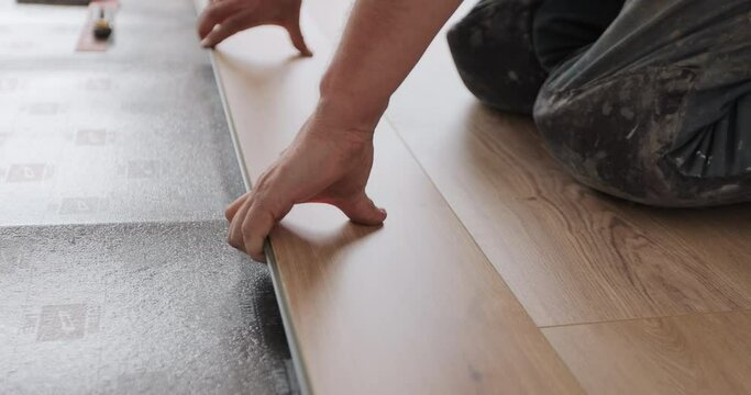 Worker, lays laminate on a black backing. Technology and process. Repair of the floor of the house.
