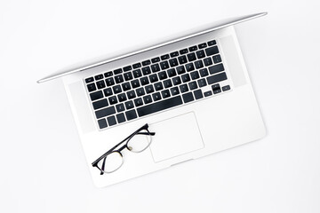 Fototapeta na wymiar Laptop and glasses on a white background, top view.